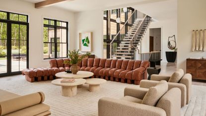 A new home in Sag Harbor a leather sofa sits in a large living room space with a round table and boucle fabric accent chairs 