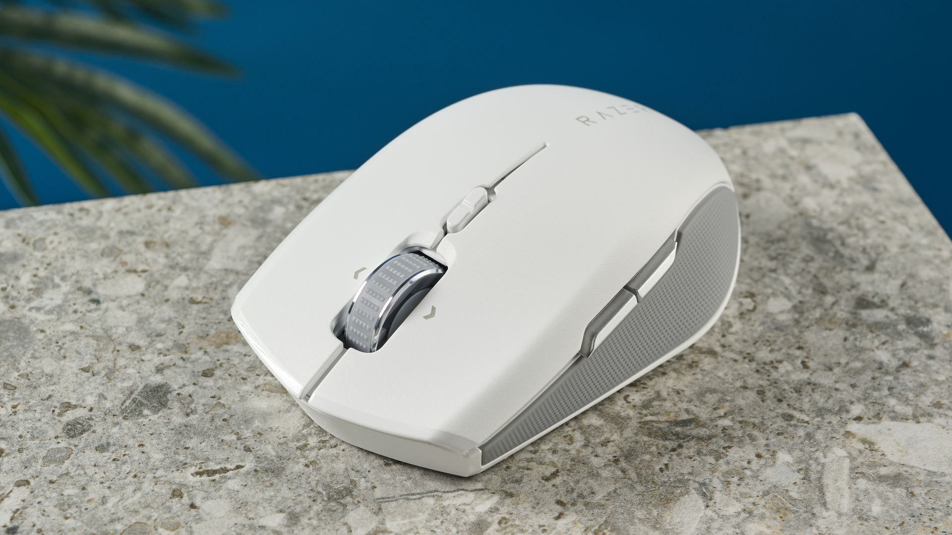 A white Razer Pro Click Mini wireless mouse on a marble slab