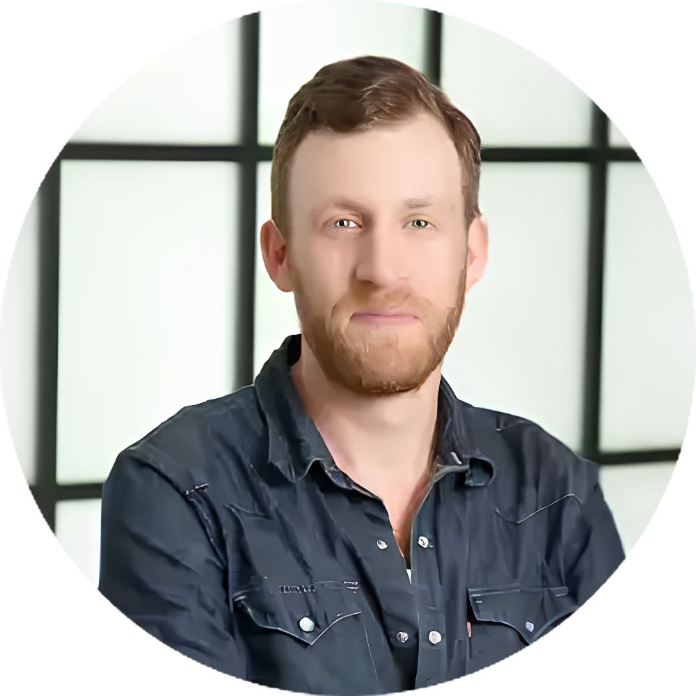 Man with reddish beard and short brown hair, wearing a dark denim shirt, circular-cropped headshot.