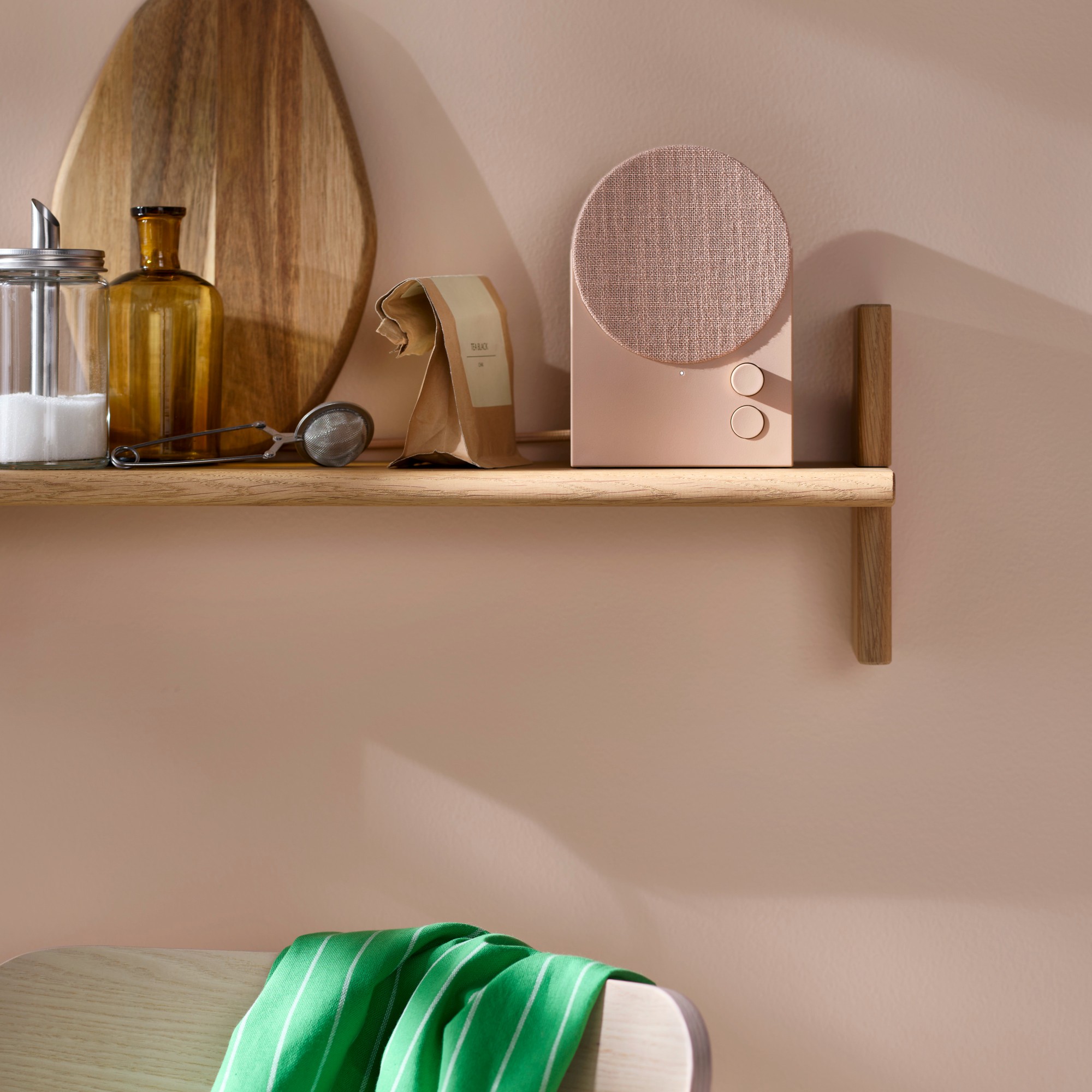 The IKEA NATTBAD bluetooth speaker in pink on a kitchen shelf against a tonal wall