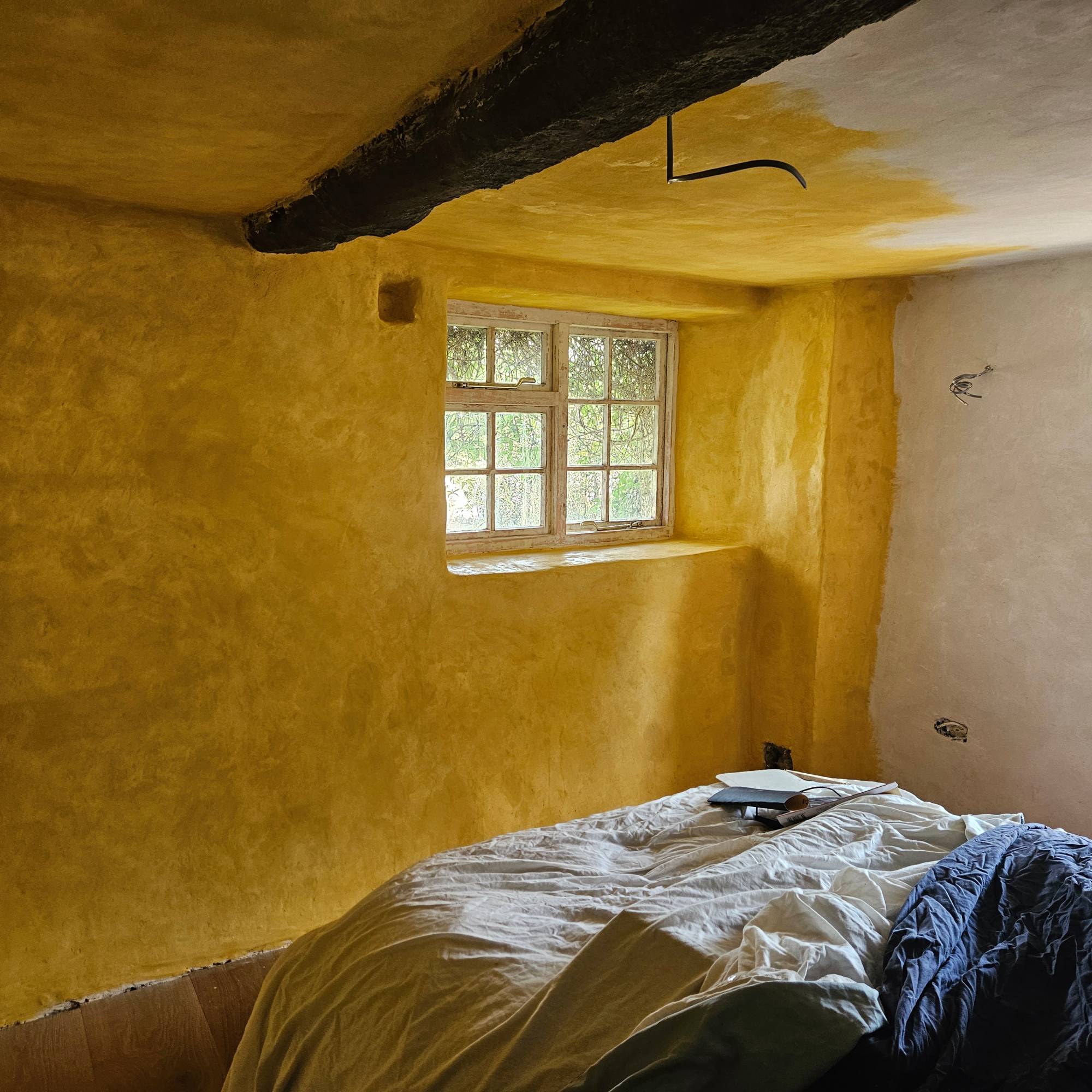 yellow mist coat on white lime plastered walls with beam on ceiling