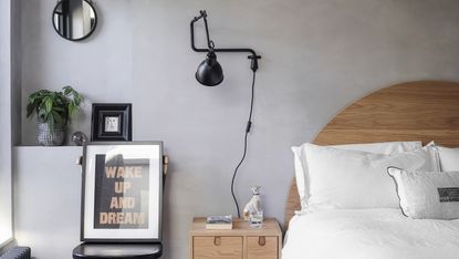 A grey bedroom with plug-in wall light