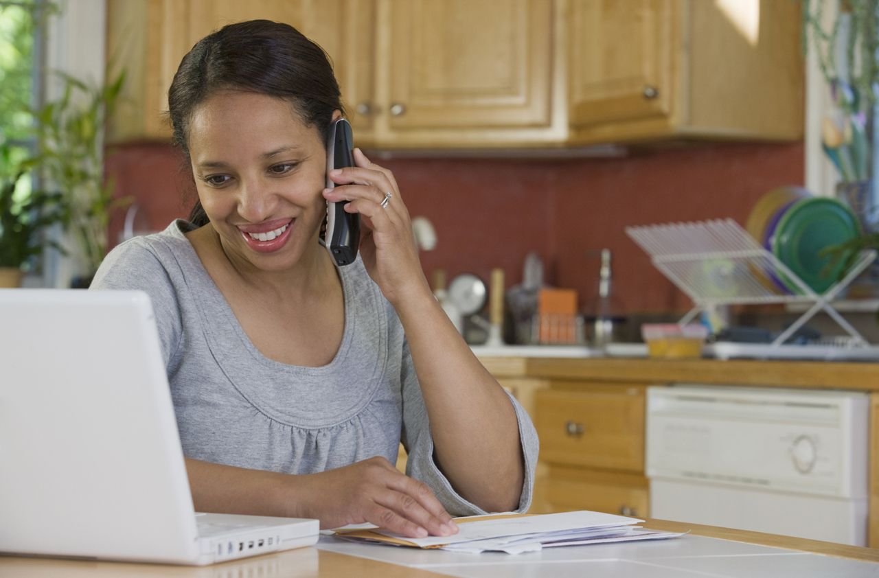 Hispanic woman working on a laptop and talking on a mobile phone