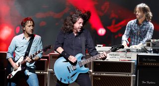 Chris Shiflett wears a faded denim shirt as he plays his Fender Cleaver Telecaster onstage with the Foo Fighters, as Dave Grohl gets lost in the moment with his Gibson DG-335 signature semi-hollow and Rami Jaffee plays keys.