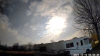 a bright light behind a cloud in the night sky illuminates a RV parked in the foreground.