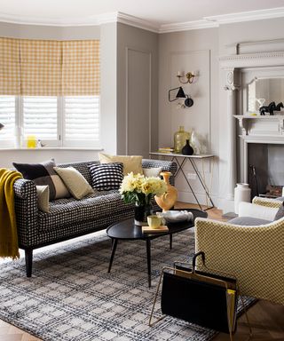 A taupe living room with yellow gingham blinds and black and yellow furniture and accessories.