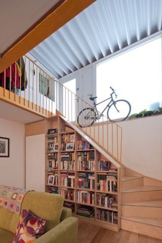 Understair bookshelves and stairs with yellow bannister leading up to front entrance