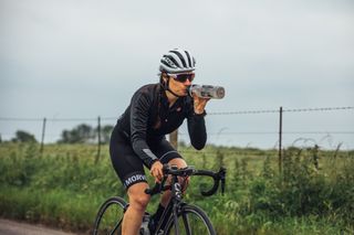 Female cyclist drinking from a water bottle while riding