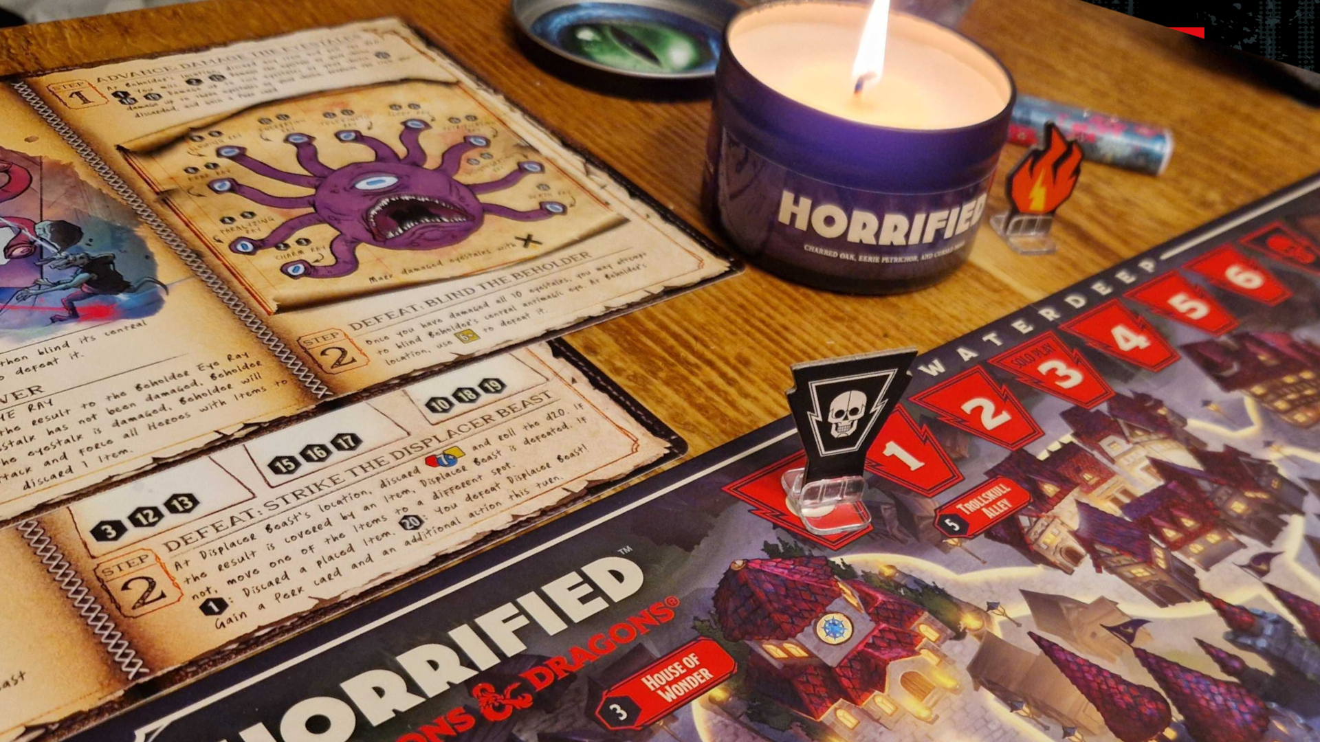 Horrified: Dungeons &amp;amp; Dragons monster cards on a wooden surface alongside the main board, tokens, and a lit candle