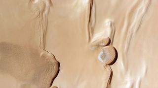 photo from mars orbit, showing rippling sand dunes to the left and some patches of water ice to the right