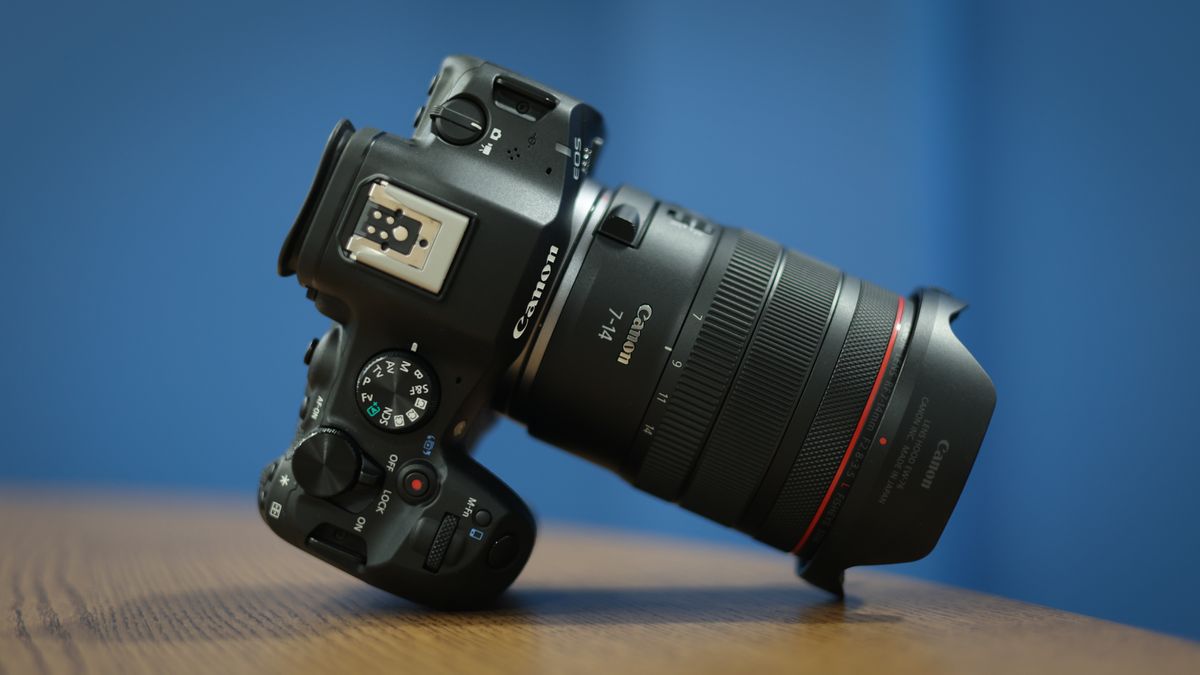 Canon RF 7-14mm f/2.8-3.5L Fisheye STM on a wooden surface in front of a blue background