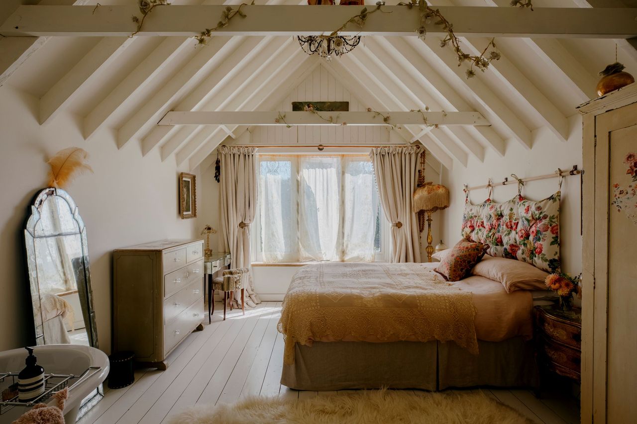 The master bedroom is upstairs with triangle wooden beams roof and painted completely white
