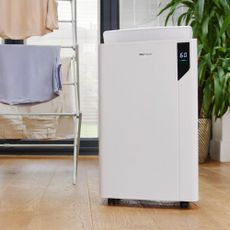 A white Pro Breeze dehumidifier next to a clothes airer with laundry on in a room with a wooden floor