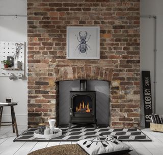 exposed brick fireplace with stove and whitewashed woof floorboards