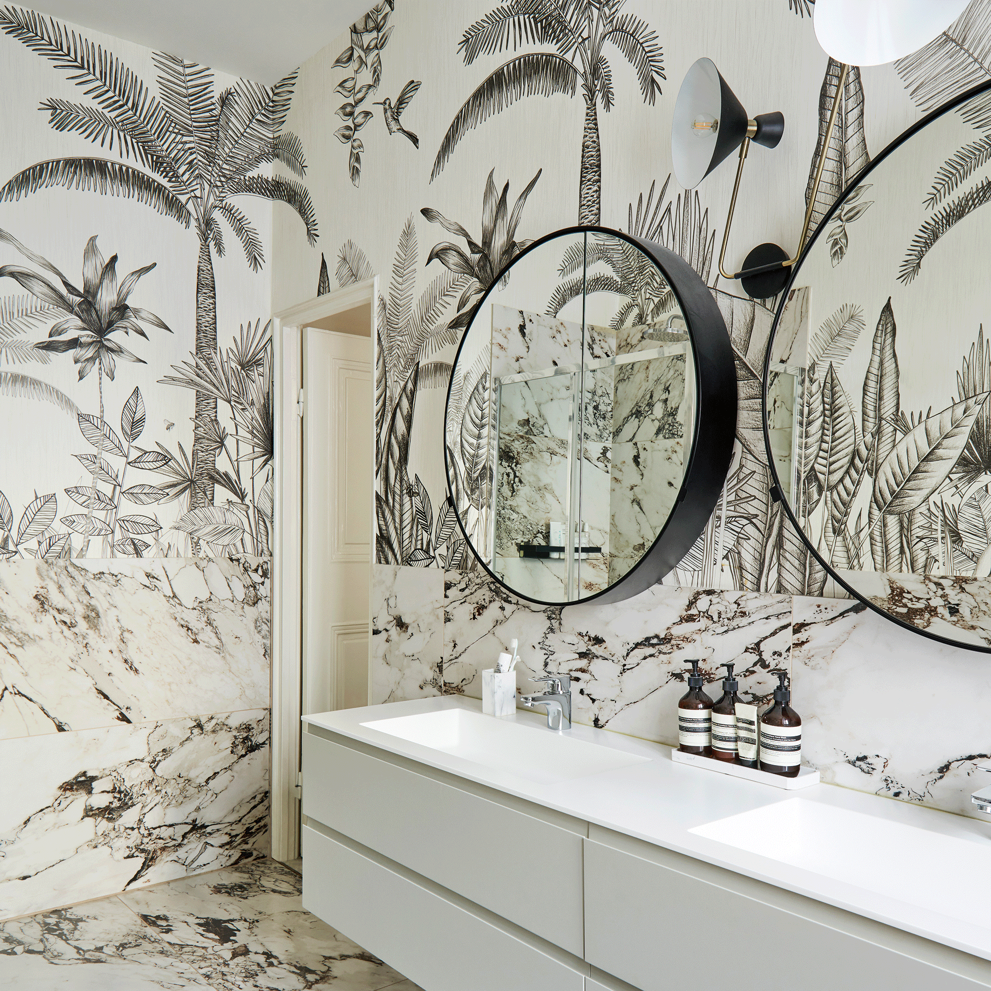 Round mirror in bathroom with palm tree wallpaper