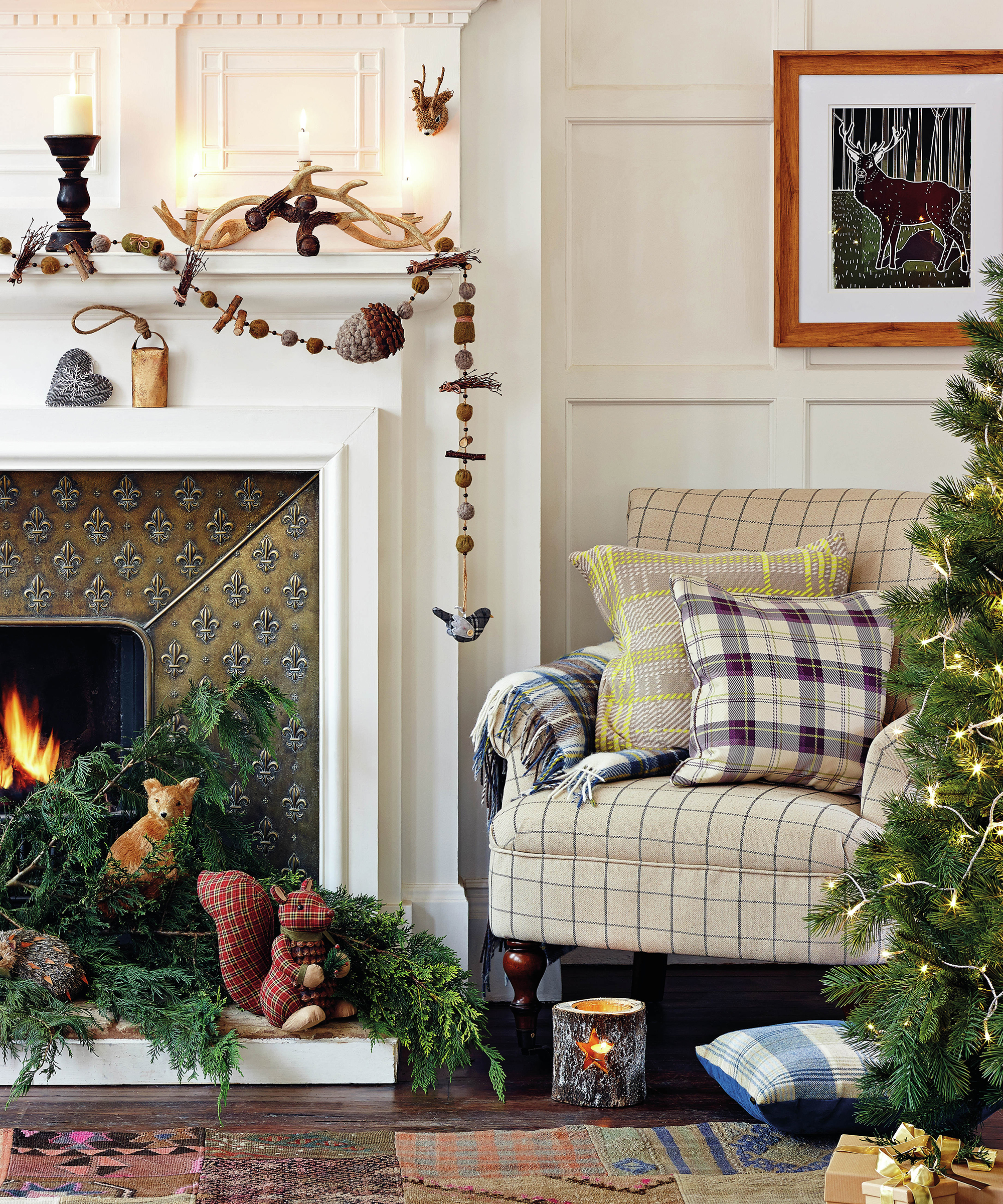 A country, rustic Christmas living room with Christmas tree, cream upholstered armchair, framed wall art, and decorated fireplace