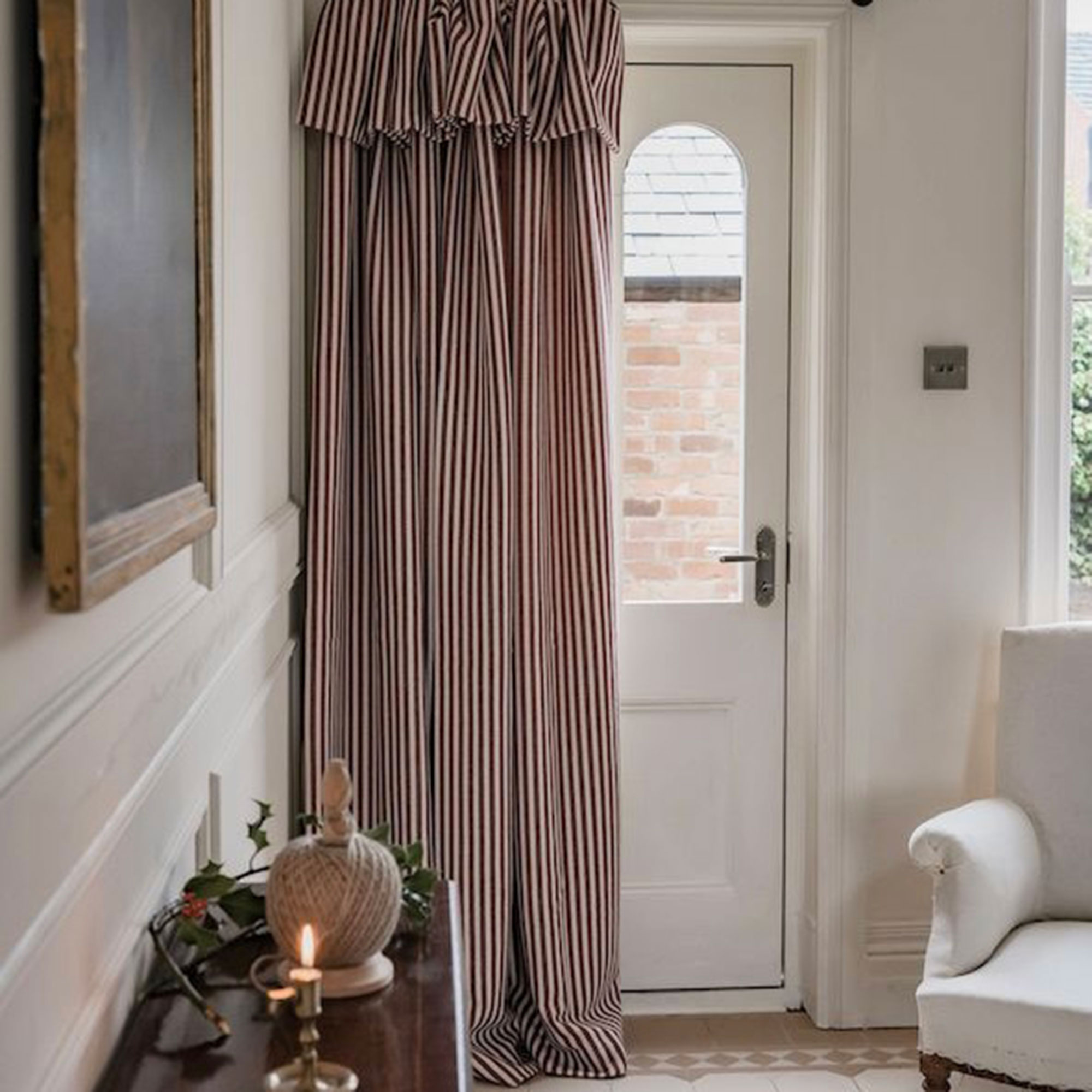 Red and white striped door curtain with ruffle in front of white door