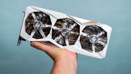 A masculine hand holds an AMD Radeon RX 7900 GRE graphics card