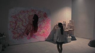 A young girl looking at a painting on the wall