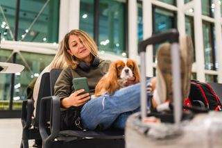 Woman sitting with her dog and luggage in the airport