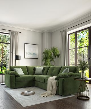 A green living room corner idea by Sofology with green velvet sofa with houseplants