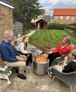 Family sat around a lit Solo Stove 2.0 Bonfire fire pit toasting marshmallows