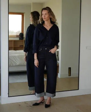 @anoukyve wearing a navy cardigan, cuffed Citizens of Humanity jeans, and kitten heel slingback pumps.