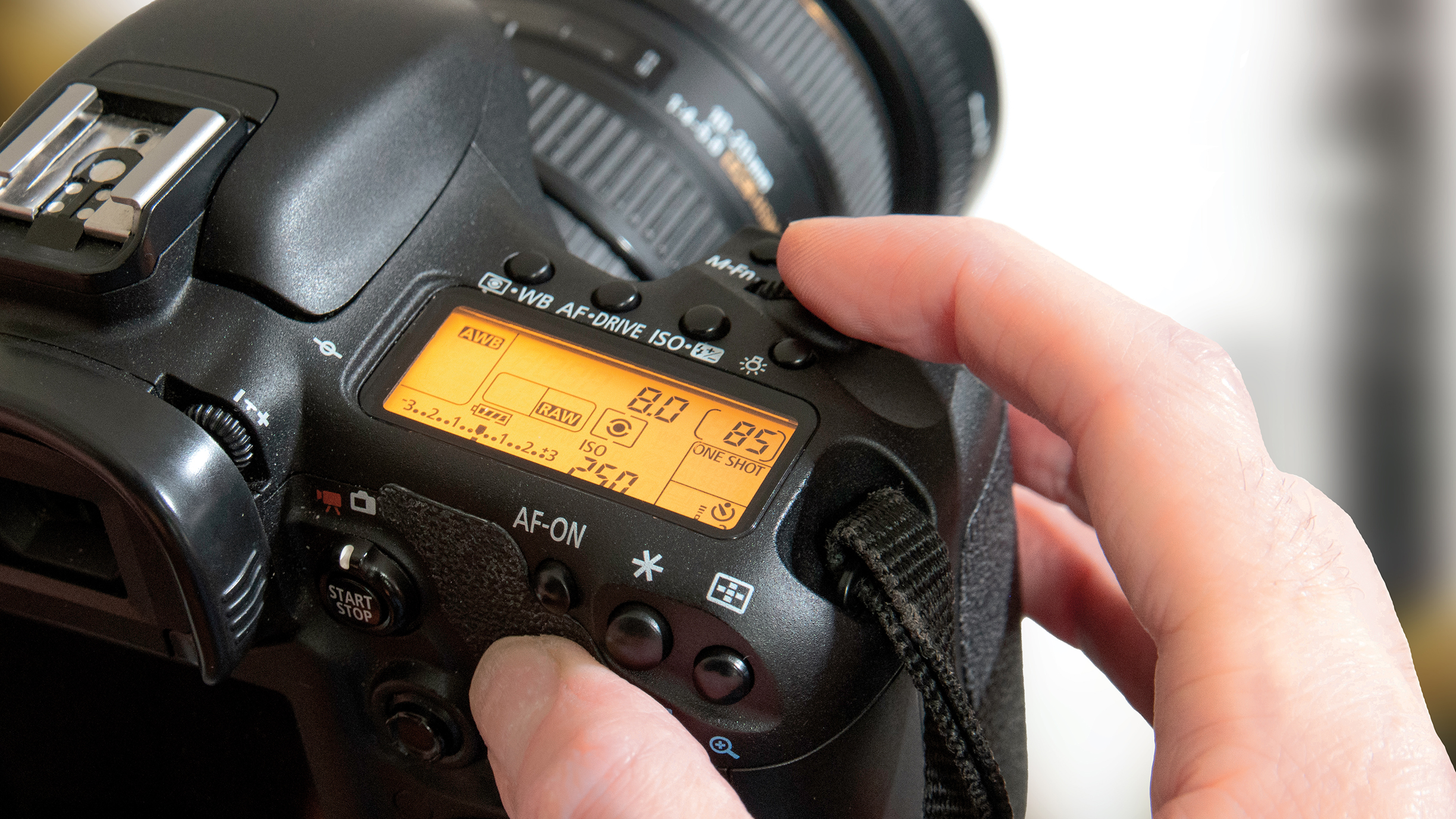 Close-up of a person&#039;s hands adjusting settings on a DSLR camera. The screen displays camera settings. The vibe is focused and tech-driven