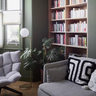 A green-painted living room with built-in bookshelves and a grey sofa and chair