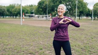 A woman jogger makes a heart shape with her hands