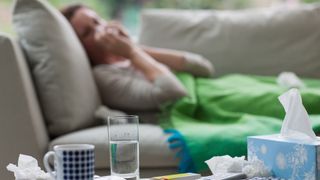 woman laying on a sofa blowing her nose