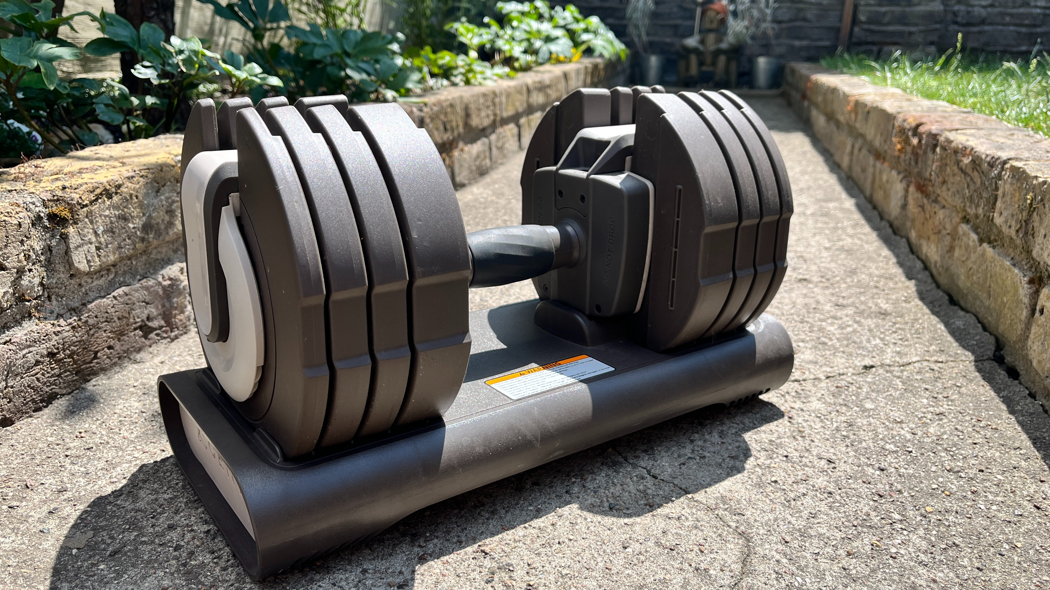 Centr Smart Stack Adjustable Dumbbell on a garden path in the sunshine