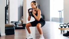 A woman doing a squat with a kettlebell