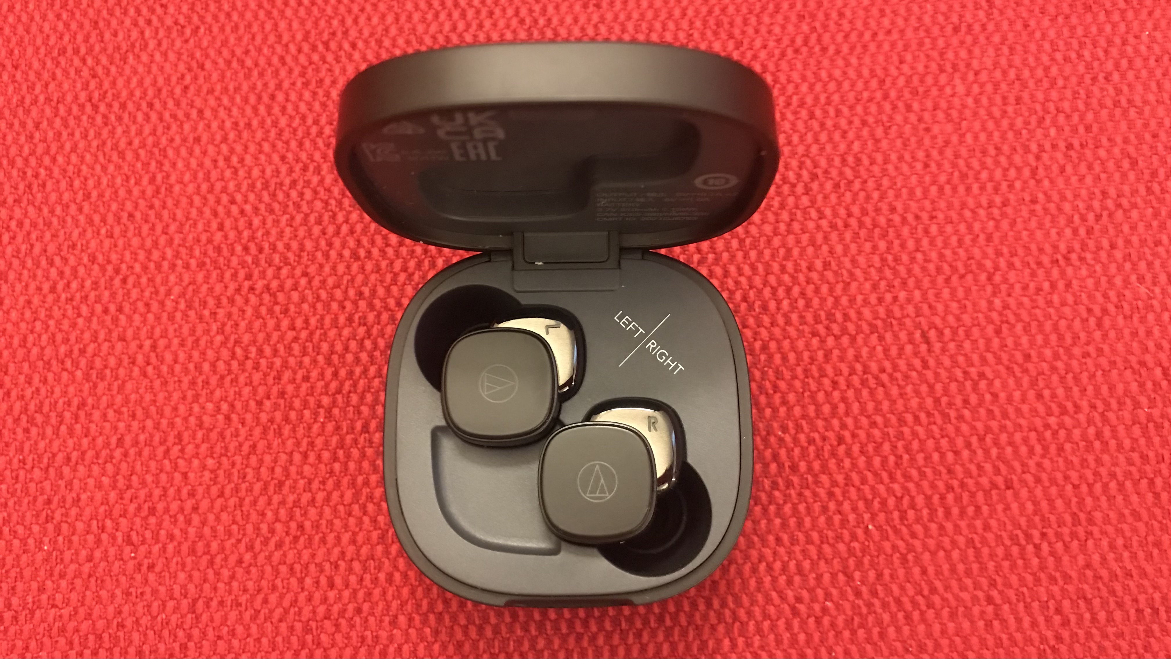 Audio-Technica ATH-SQ1TW earphones and case on red background