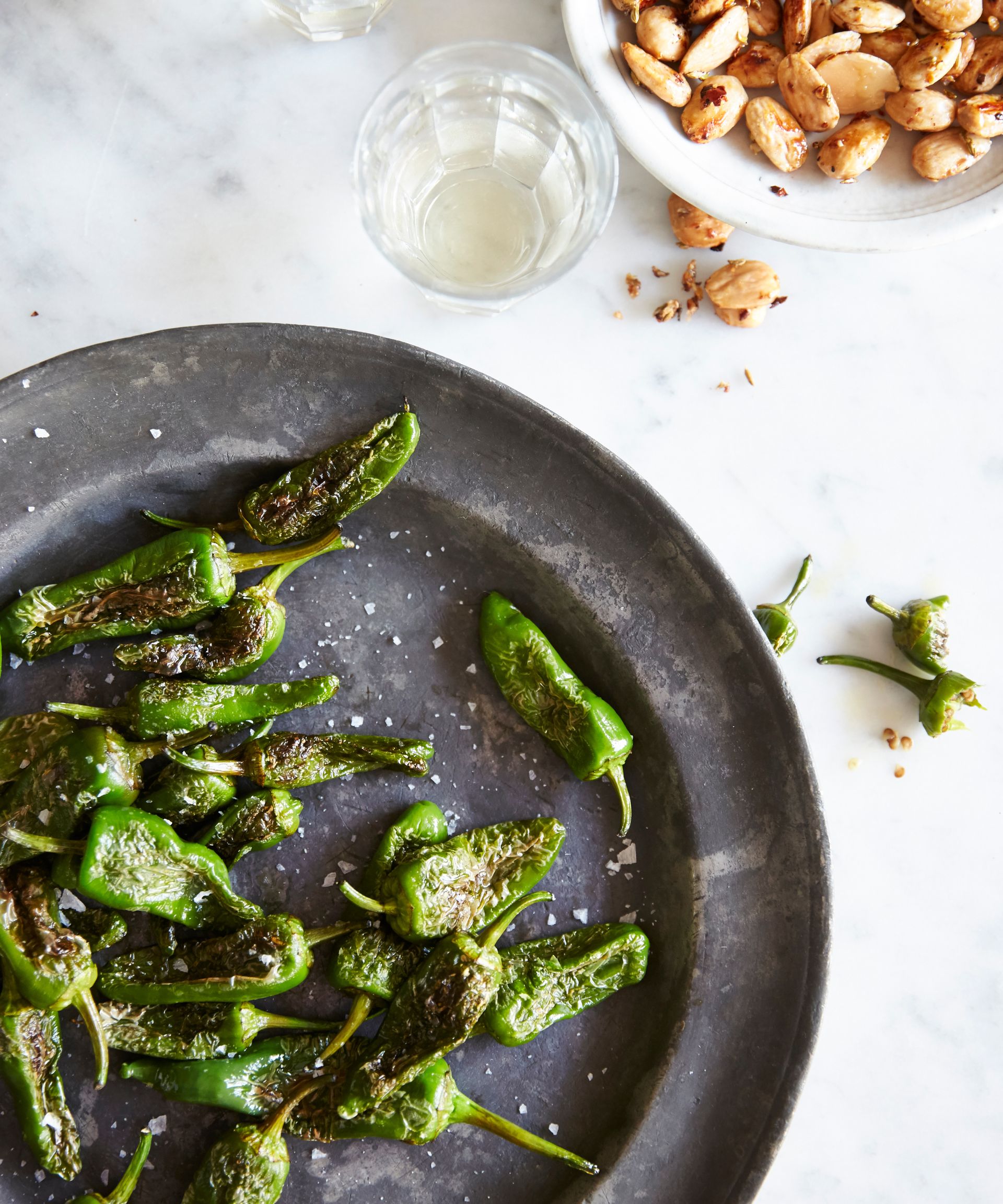 Padron peppers recipe on a black plate with almonds
