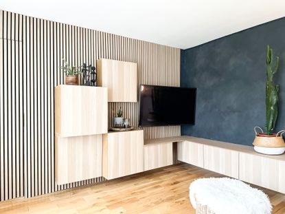 A living room with a wood panelled wall with cabinets fixed to it in a asymmetrical pattern