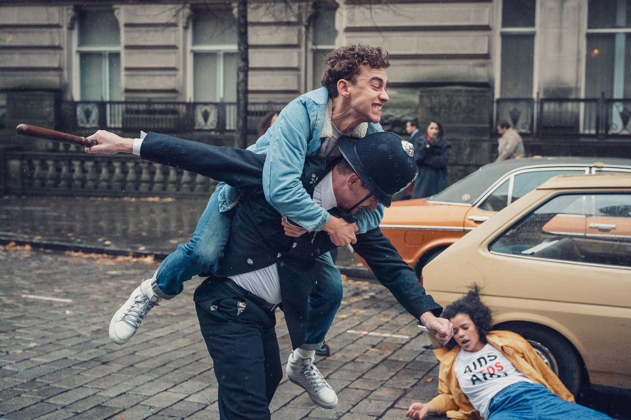 Olly Alexander as Ritchie and Lydia West as Jill battling the police in "It's A Sin."