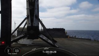 a black and white rocket rests on the deck of a ship at sea on a cloudy day