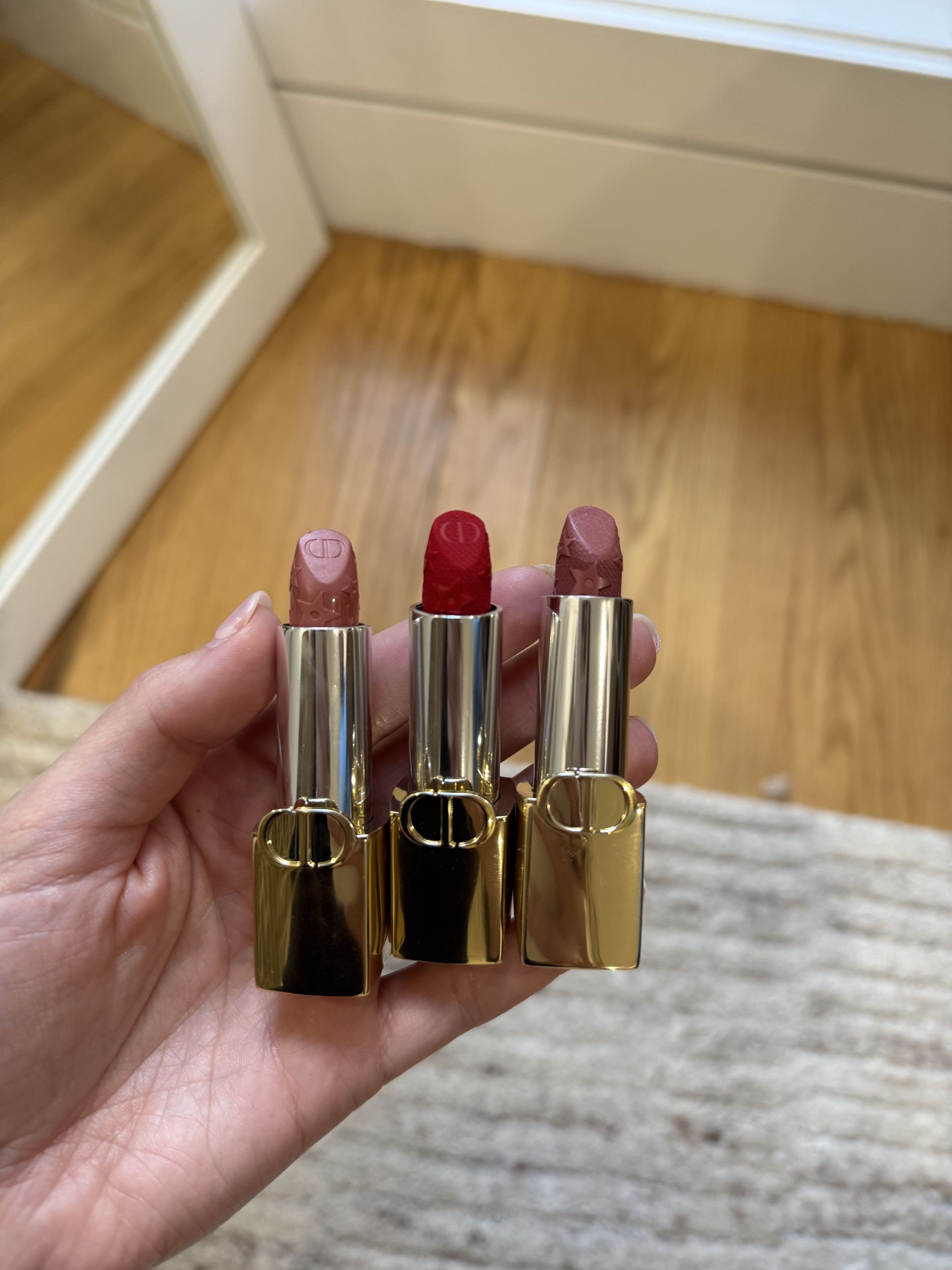 Jamie Schneider holding three lipsticks from Dior's 2025 holiday makeup collection.