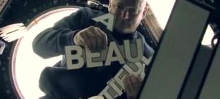 Astronaut Mark Kelly spells out a message ("It's a beautiful day") while floating on the International Space Station during a video appearance at a U2 concert in Seattle June 5.