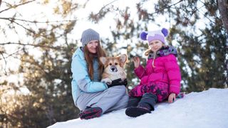 Mother and daughter with corgi in the snow