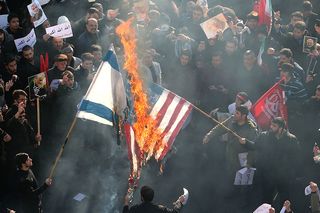 US and an Israeli flags on fire © ATTA KENARE/AFP via Getty Images