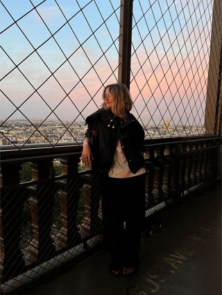 Eliza Huber wearing a Proenza Schouler technical jacket with a white COS shirt and Aritzia poplin black pants in the Eiffel Tower at sunset.