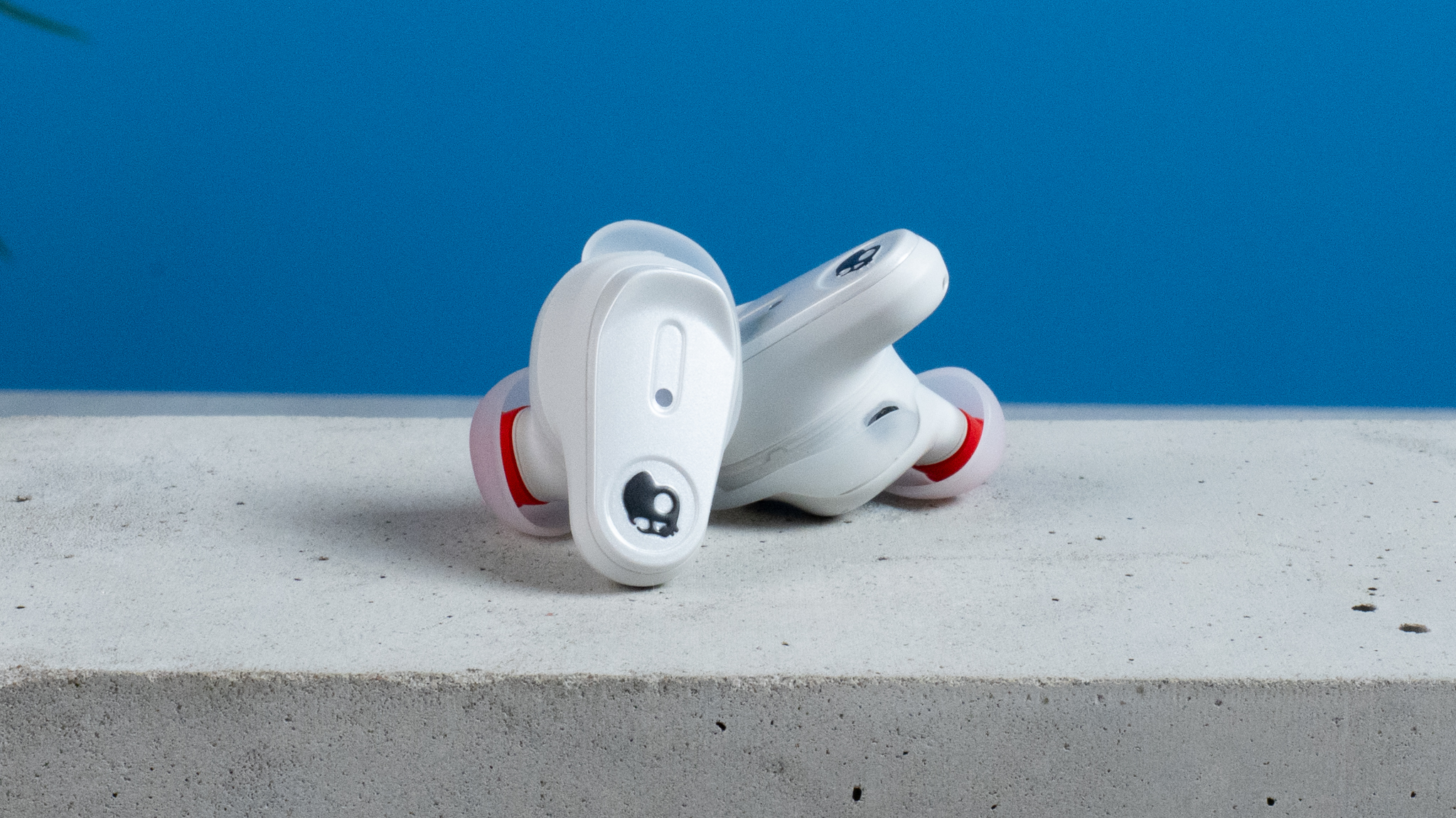 the skullcandy x bose method 360 anc earbuds in white, with a long charging case, a carabiner clip, and various silicone tip sizes