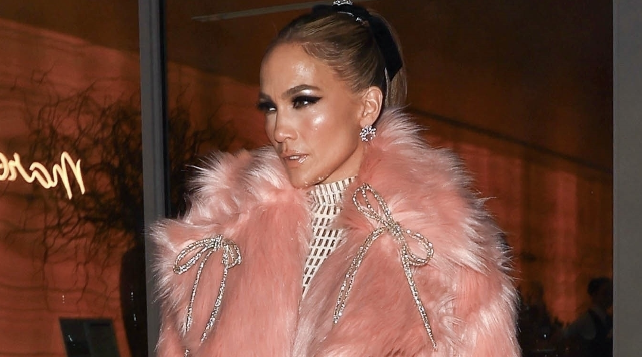 Jennifer Lopez looks pretty in pink as she steps out in a flirty, mid-length pink fur coat adorned with silver bows, layered over a white floor-length turtleneck gown, and finished off with heels and a chic bag, while leaving dinner in Beverly Hills after the GRAMMYs.