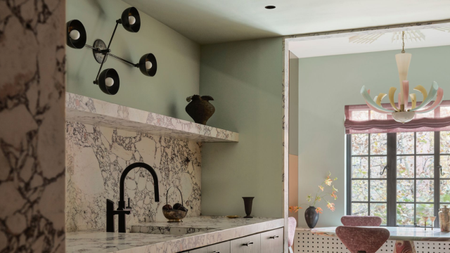 mint green kitchen with marble counters and a chandelier used as a wall light above the sink
