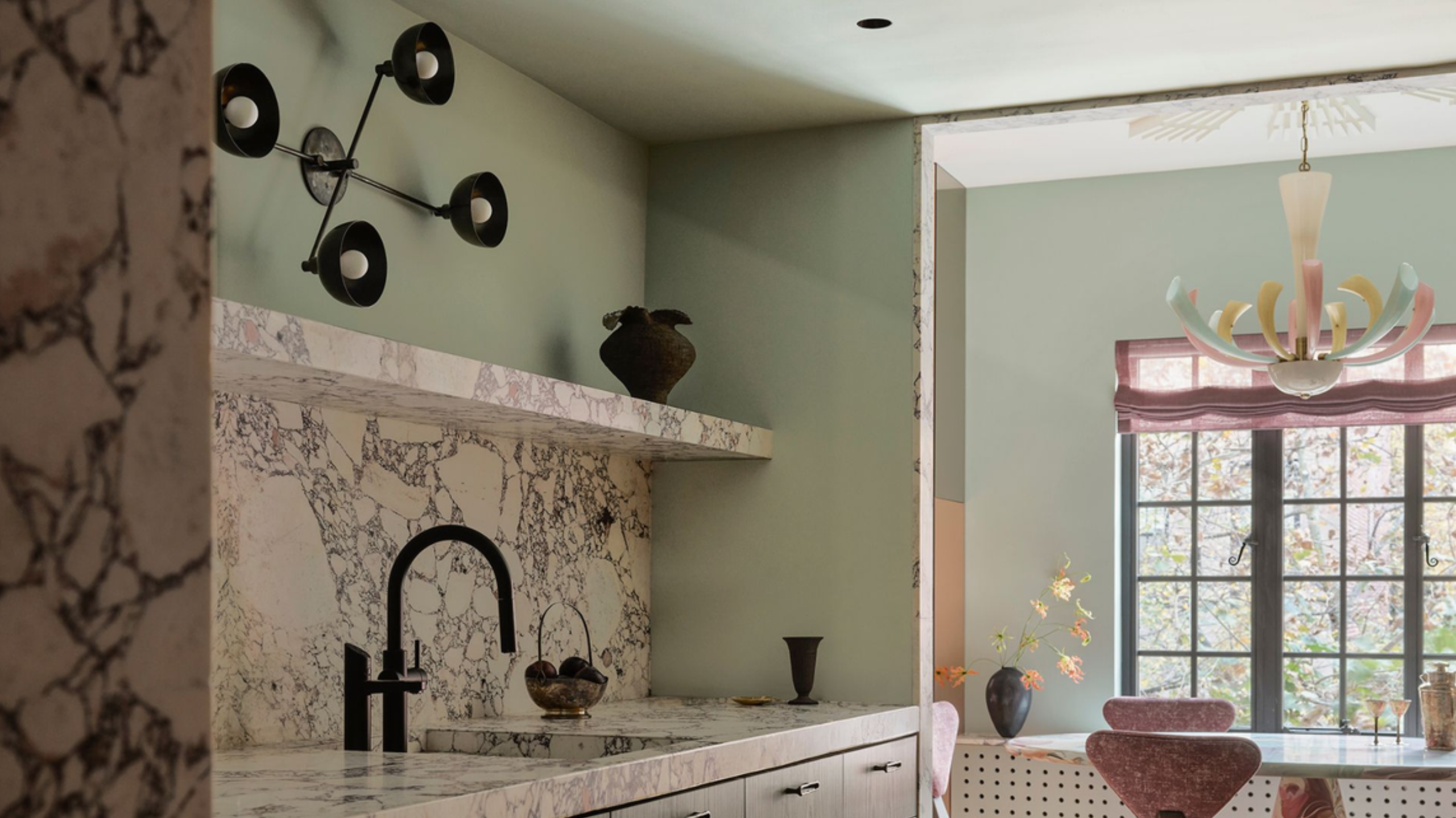 mint green kitchen with marble counters and a chandelier used as a wall light above the sink