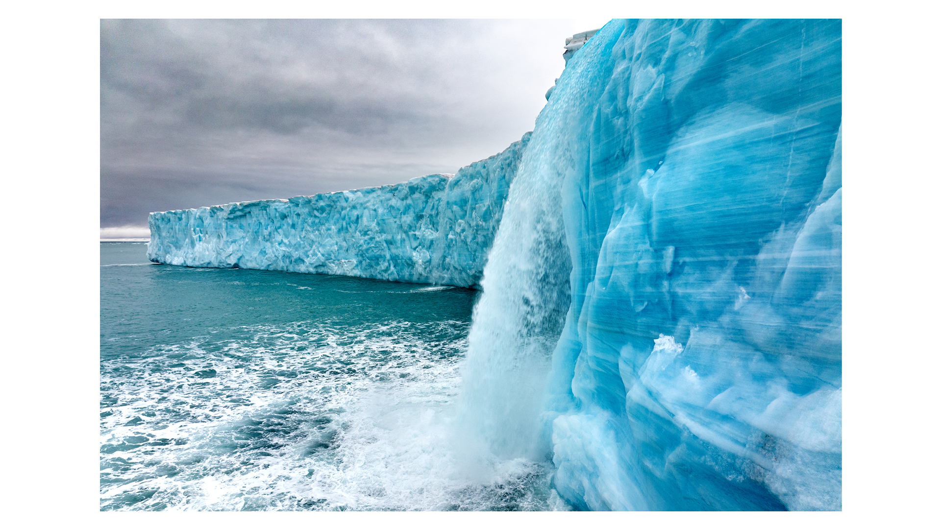 Phtotograph of Meltwater cascading down an ice wall in Bråsvellbreen, Svalbard, by Roie Galitz, winner of the Planet Earth – Landscape, Climate & Water Portfolio category in Travel Photographer of the Year 2024.
