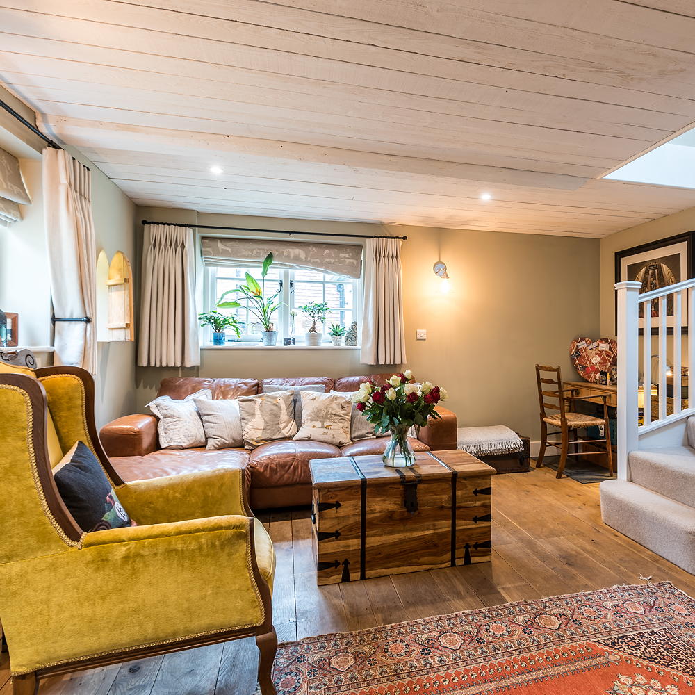 The living room in The Stable in Wiltshire, with leather sofa and mustard coloured armchair