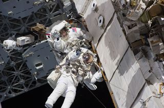 Astronauts Steve Bowen and Alvin Drew wave during the first spacewalk of their STS-133 mission on Feb. 28, 2011